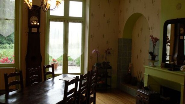 A dining room with a wooden table and chairs, a chandelier, a clock, and a view through a door to a garden. - Stay in the heart of Joan of Arc's land with 4 unique rooms (Montigny-lès-Vaucouleurs)