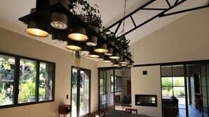 Un comedor moderno con una mesa larga, varias sillas, luces colgantes y ventanas amplias que dan a zonas verdes.