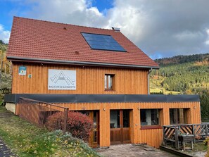 A wooden building with a red-tiled roof, a sign for 'BALCON de la ZIMETTE,' and a view of a forested hillside. - Charming mountain B&B rooms, pets allowed with approval (Ventron)