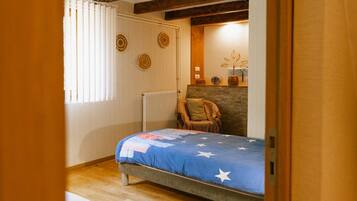 Un dormitorio con cama, una silla, un radiador, una pared con decoraciones circulares y una lámpara de techo.