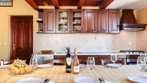 Una cocina con armarios de madera, salpicadero de azulejos y una mesa de comedor lista para una comida.