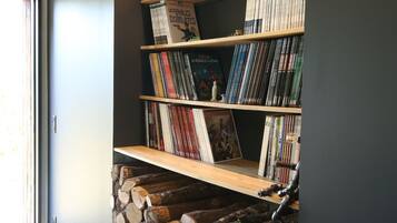 Een boekenplank vol boeken en dvd's, een houten plank, en een stapelhout.'