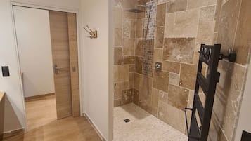 Zona de ducha con paredes de azulejos y suelo de madera.