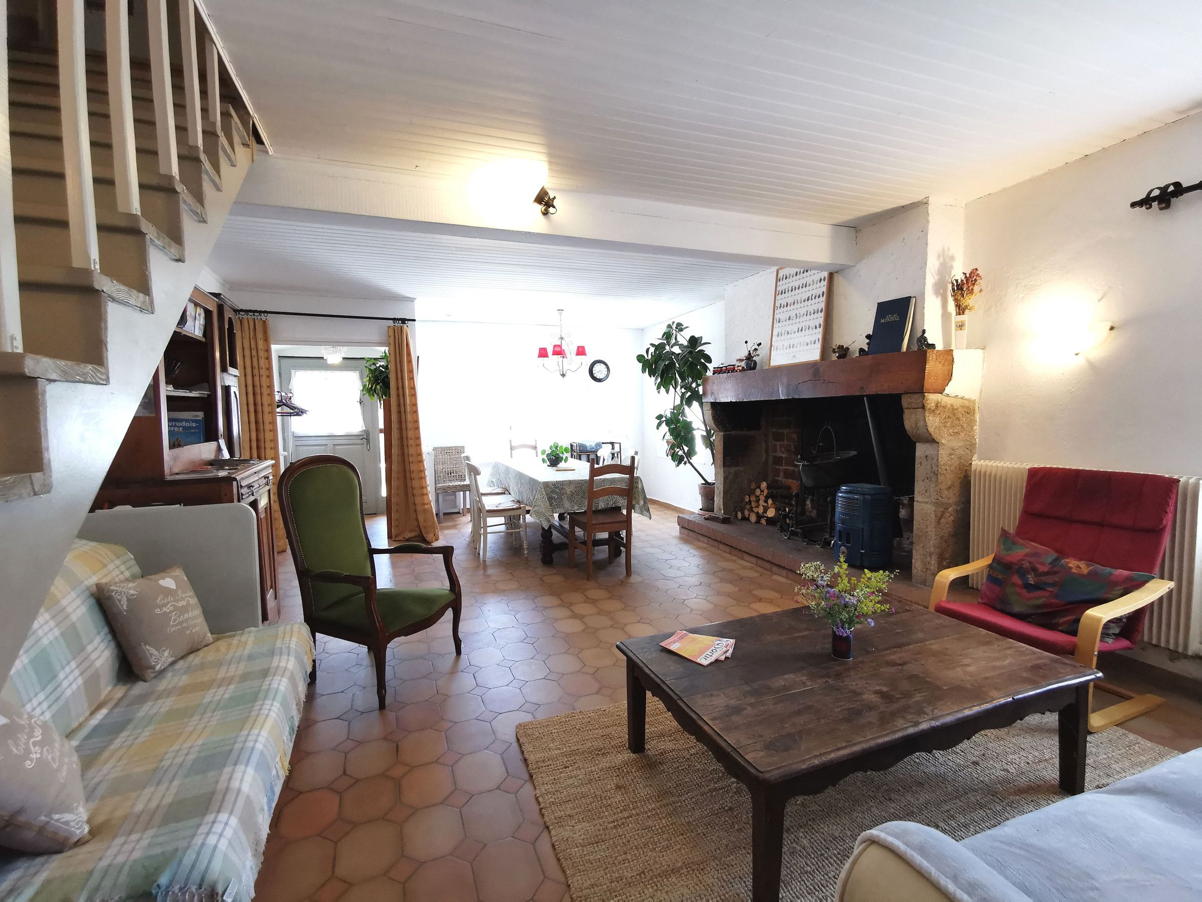 Un salon chaleureux avec une cheminée, un coin repas et un escalier menant à l’étage supérieur.