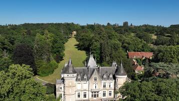 Un vaste château historique, doté de nombreuses tours et d’une pelouse bien entretenue.