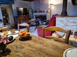 A cozy living room with a wooden dining table, a red armchair, and a television. - Cozy room with sitting area and breakfast included (Châteauroux)