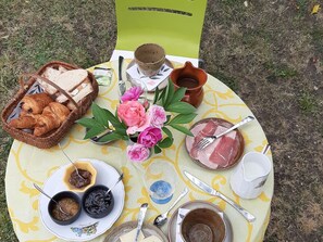 A picnic setup with bread, pastries, flowers, and various dishes on a table outdoors. - Cozy room with sitting area and breakfast included (Châteauroux)