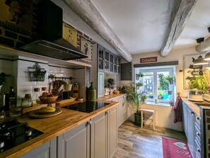Een keuken met houten aanrechtbladen, witte kasten en uitzicht naar buiten.