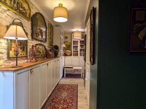 A hallway with a stone wall, wooden counter, and a red patterned rug.