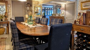 A dining area with a wooden table, plaid chairs, and a wine rack.