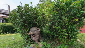 A garden with a lion statue surrounded by greenery and rocks.