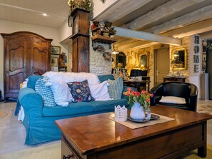 A cozy living room with a teal sofa, a wooden coffee table, and a stone fireplace.