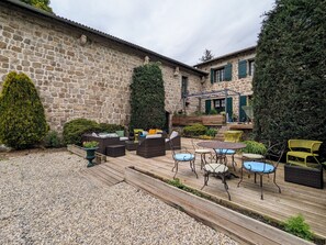 A courtyard with stone walls, outdoor furniture, and a wooden deck.