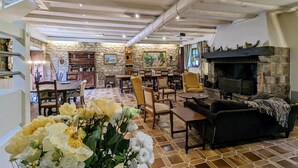 Un vaste espace de vie agrémenté d’un mur en pierre, d’une cheminée et d’un coin repas avec des meubles en bois.