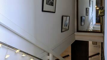A staircase with a white wall, a framed picture, and a mirror reflecting part of the room.