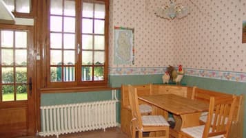 Un comedor con una mesa y sillas de madera, un radiador debajo de una ventana y una pared con estampado de lunares.