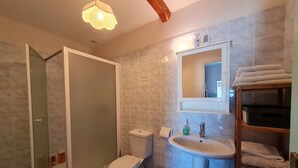 Une salle de bain équipée d’une douche, de toilettes, d’un lavabo et d’un miroir au-dessus du lavabo.
