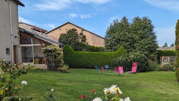 Una proprietà residenziale con un prato curato, un edificio in mattoni e un giardino con sedie.
