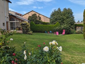A residential property with a well-maintained lawn, a brick building, and a garden with chairs. - Family home with fireplace, garden, and WiFi in Esley, Vosges (Esley)