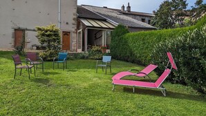 Una casa con patio arredato e un prato curato.