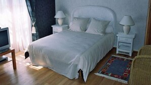 Une chambre à coucher bien rangée, avec un lit, deux tables de chevet dotées de lampes, un téléviseur et un tapis à motifs.