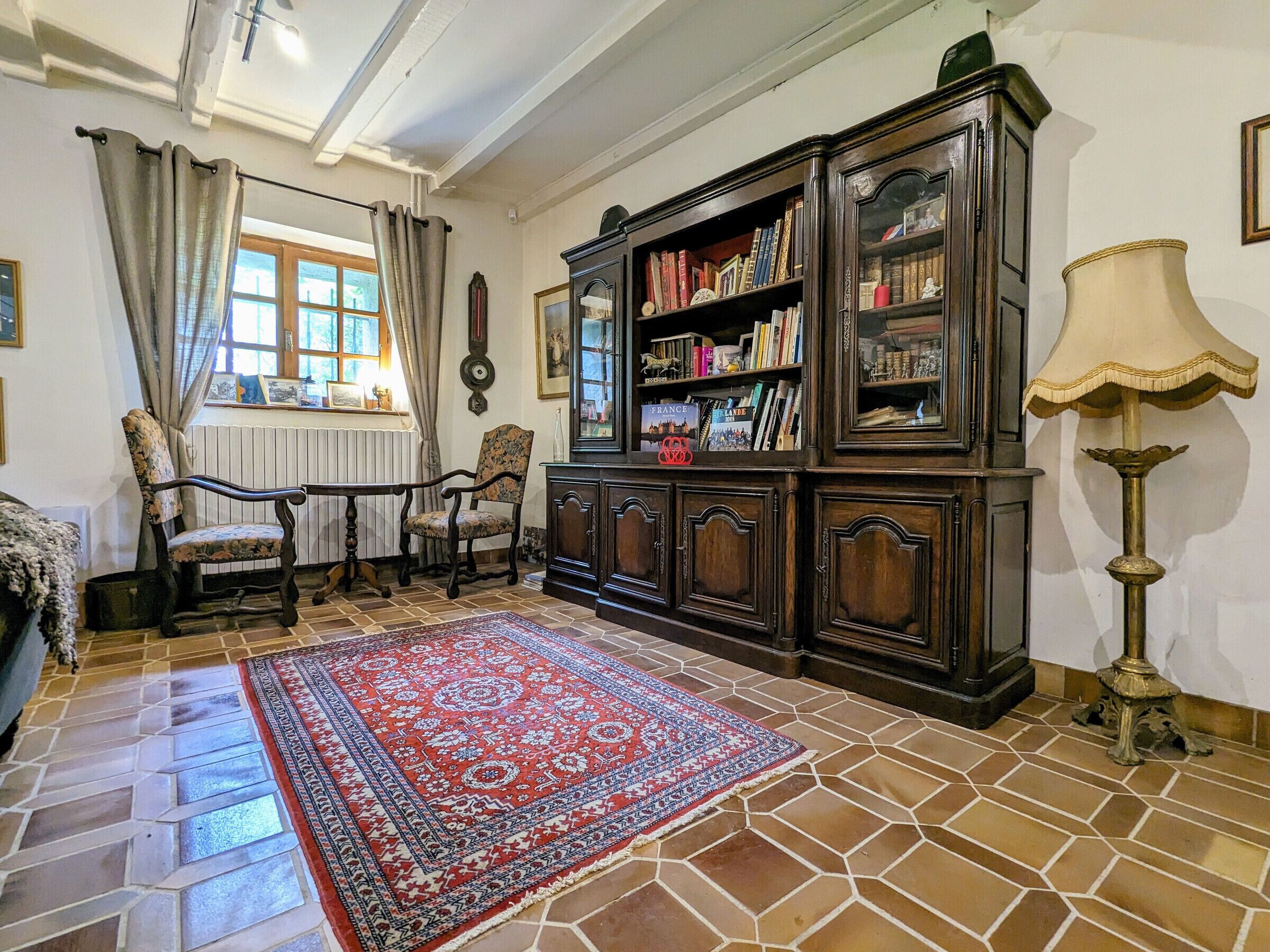 A traditional room with a patterned rug, wooden furniture, and a bookshelf.