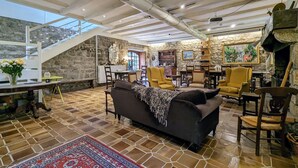 A spacious living area with a high ceiling, stone walls, and a dining area with wooden furniture.