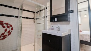 Une salle de bain moderne avec une douche à parois de verre, un lavabo blanc et un meuble-lavabo foncé.