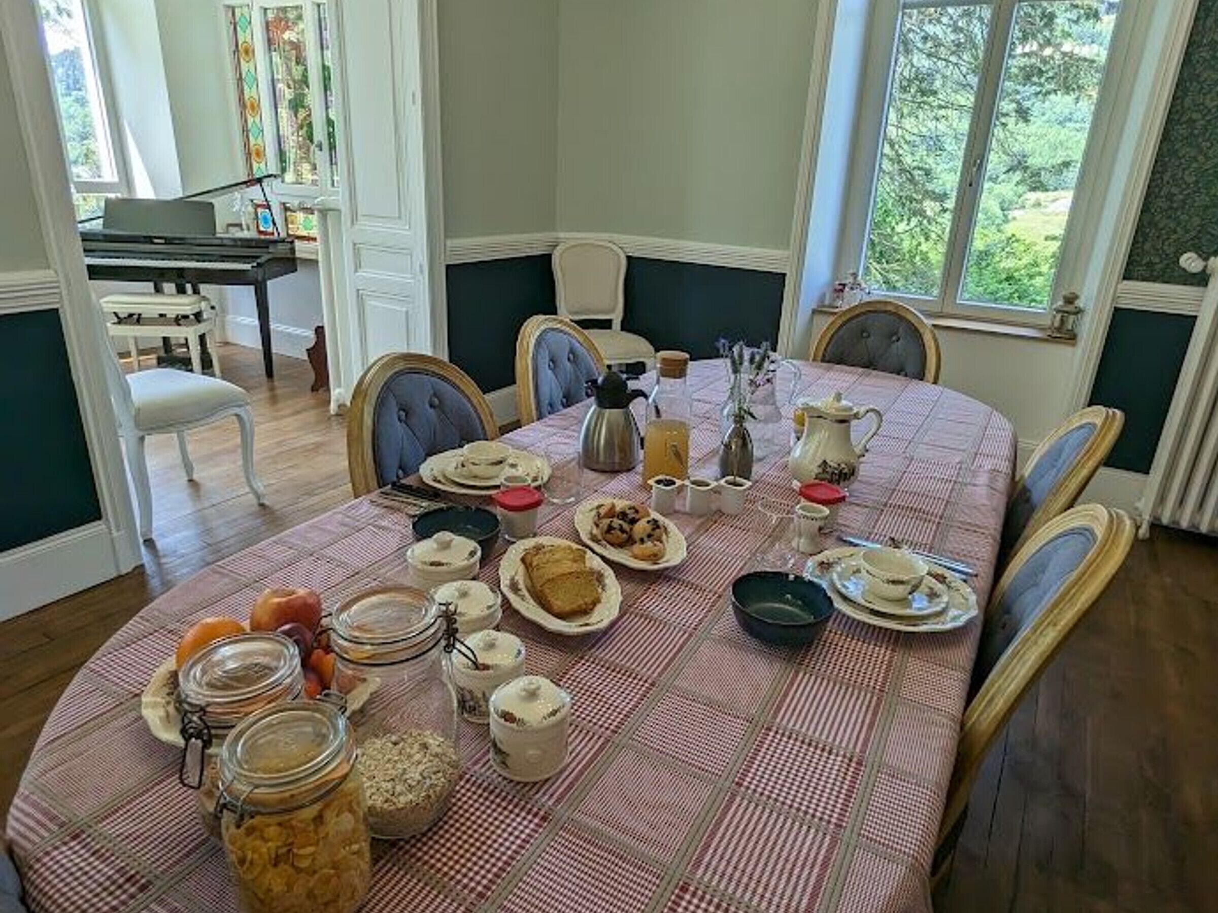Una mesa de comedor dispuesta con varios platos, frascos y un piano al fondo.