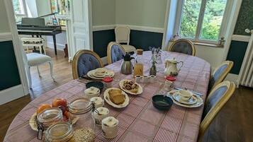 Una mesa de comedor dispuesta con varios platos, frascos y un piano al fondo.