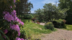 A garden area with a gravel path, a wooden table and chairs, and a lamp post.