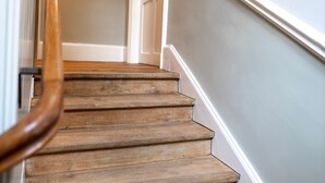 A wooden staircase with a handrail, leading to a door.