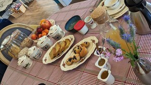 A breakfast table set with various food items, including fruits, pastries, and condiments, on a checkered tablecloth.