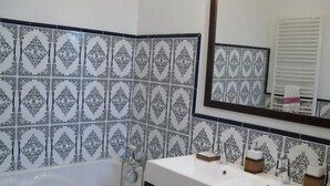 Un baño con un lavamanos blanco, dos espejos y baldosas estampadas.