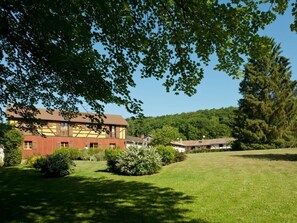 A traditional building with a sloped roof, surrounded by a well-maintained lawn and dense trees. - Elegant rooms in the heart of the Argonne forest (Futeau)