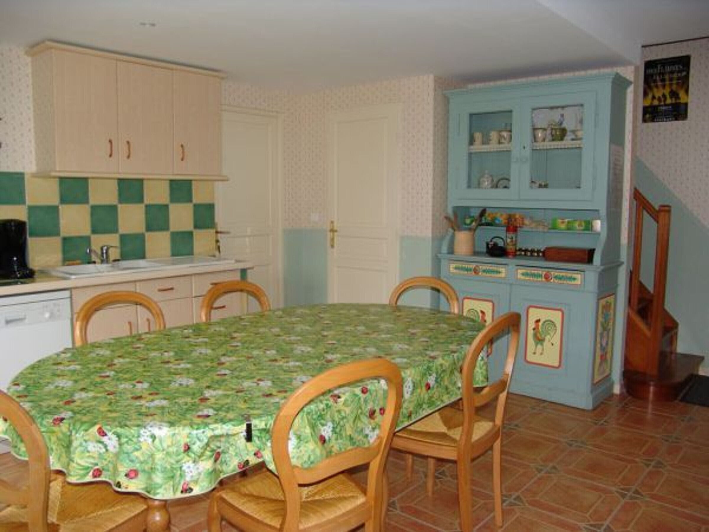Une cuisine avec un crédence à carreaux, une table à manger avec des chaises et un buffet bleu doté de poignées décoratives.