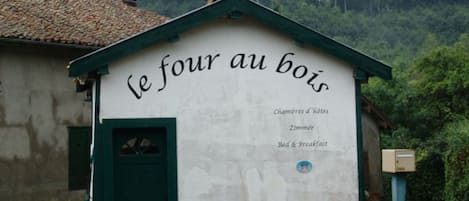 A rustic building with a sign reading "le four au bois" indicating it is a bed and breakfast.