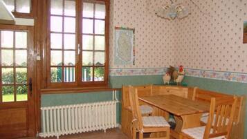 A dining area with a wooden table and chairs, a radiator below a window, and a wall with a polka dot pattern.