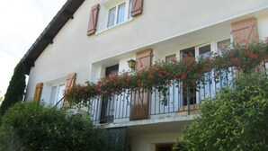 Un edificio de dos pisos con un balcón decorado con flores rojas.
