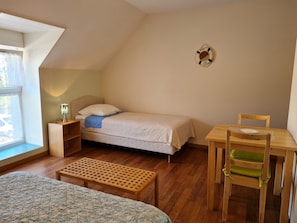 A small, cozy room with a single bed, a wooden desk with a chair, a small table, and a window. - Spacious rooms near Beaugency, breakfast included (Cravant)