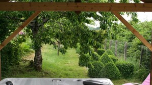 Un jacuzzi bajo un pérgola de madera con vistas a un jardín exuberante y una piscina.