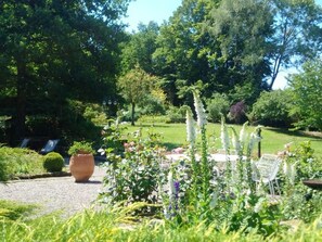 Un jardin où l’on trouve une grande variété de plantes, avec un grand pot placé au premier plan.