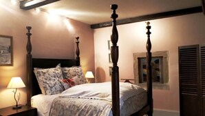 A four-poster bed with a wooden headboard, a nightstand with a lamp, and a painting on the wall. - Family suite at Priory with park access and spacious rooms (Aydoilles)