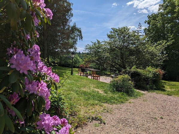 A garden area with a gravel path, a wooden table and chairs, and a lamp post. - Gentiane Room - 2 Double Beds & Sauna, Perfect for Families (Sapois)