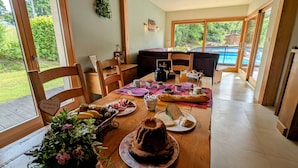 A dining area with a wooden table set for breakfast, featuring bread, pastries, and a cake. - Spacious room with pool, spa, and hammam (Anould)