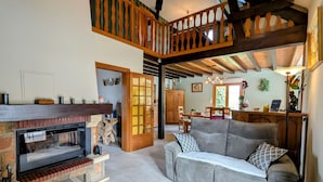 A spacious living area with a fireplace, a sofa, and a dining table. - Spacious room with pool, spa, and hammam (Anould)