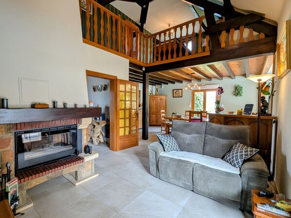 A spacious living area with a fireplace, a sofa, and a dining table. - Spacious room with pool, spa, and hammam (Anould)
