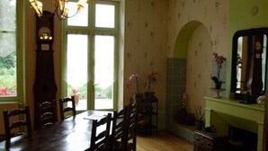 A dining area with a wooden table and chairs, a chandelier, a clock, and a fireplace.