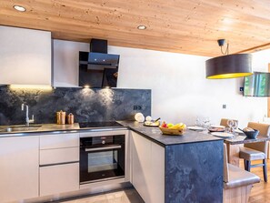 A modern kitchen with a built-in oven, a sink, and a dining area with a table and chairs.