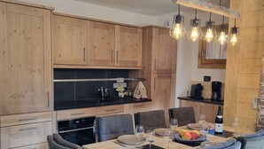A modern kitchen with wooden cabinets, a black countertop, and a dining area with a wooden table and chairs.